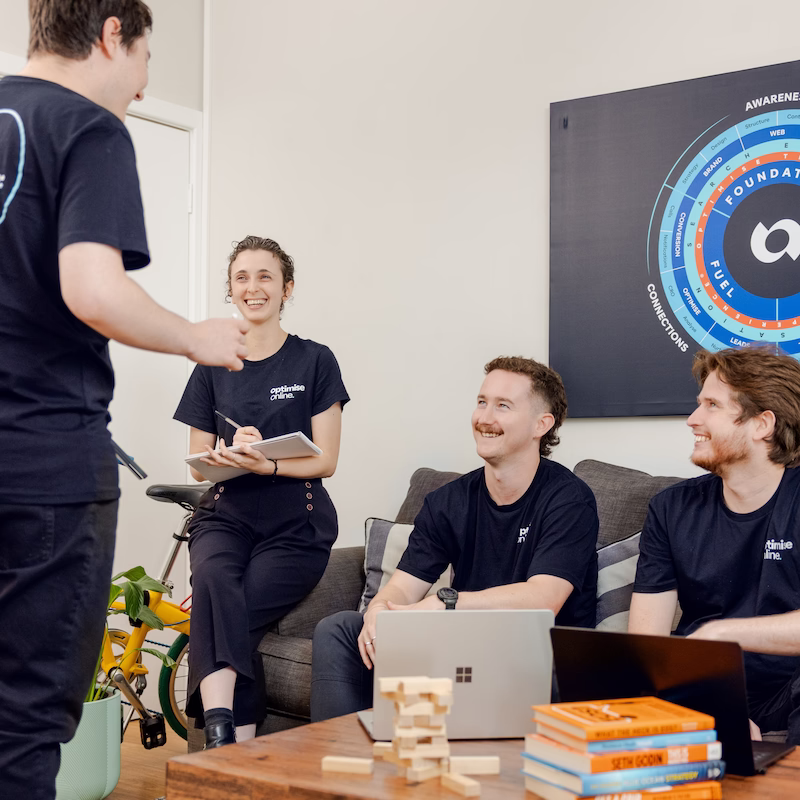 Optimise Online team members discussing strategy in a relaxed office setting